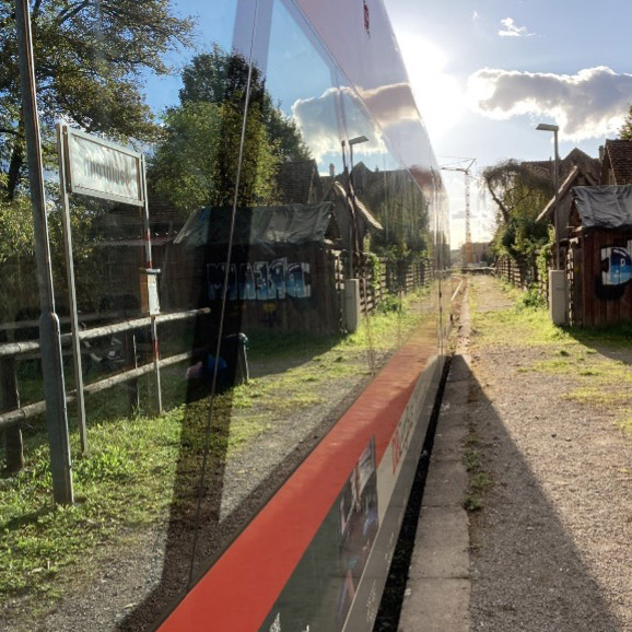 Letzter Saison-Zug am 15.10.2023 – das Bahnhofsschild spiegelt sich im Fensterband des Freizeitexpress Kloster Maulbronn in der Abendsonne.